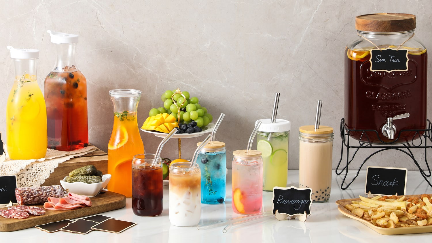 A laid table with glass carafes, lidded tumblers with straws and small chalkboard labels